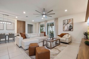 A modern living room with a sectional sofa, a coffee table, and a ceiling fan. - Disney Dream Home Mario, Frozen & Minions (Davenport)