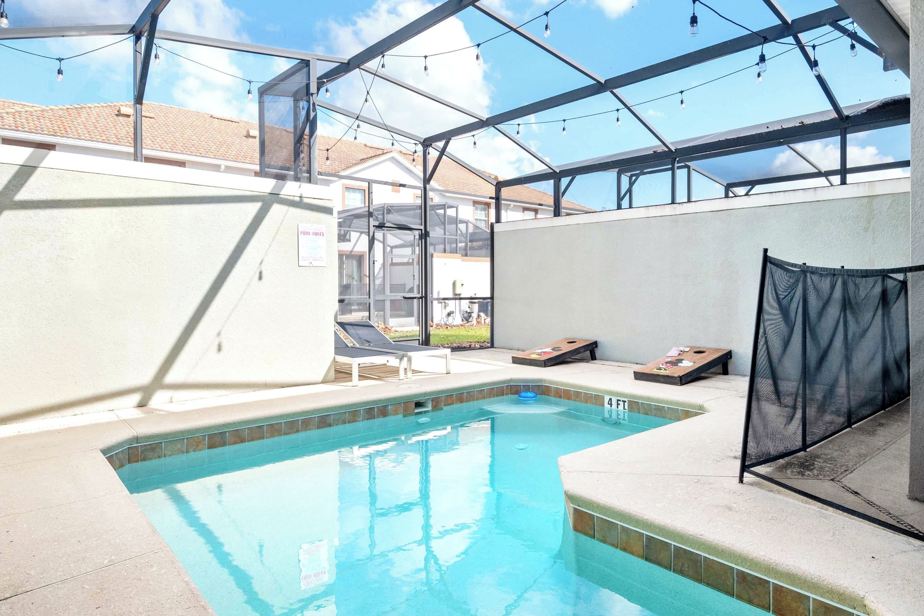 Una piscina interior con techo de vidrio, sillones de descanso y vistas al vecindario.