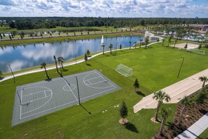 A basketball court with a water body and trees in the background. - Solara 9BR Lakeview Estate With Private Spa & Themed Suites (Kissimmee)