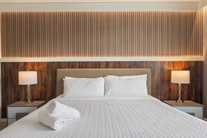 Une chambre d’hôtel avec un grand lit, deux tables de chevet avec des lampes et un mur recouvert de panneaux en bois.