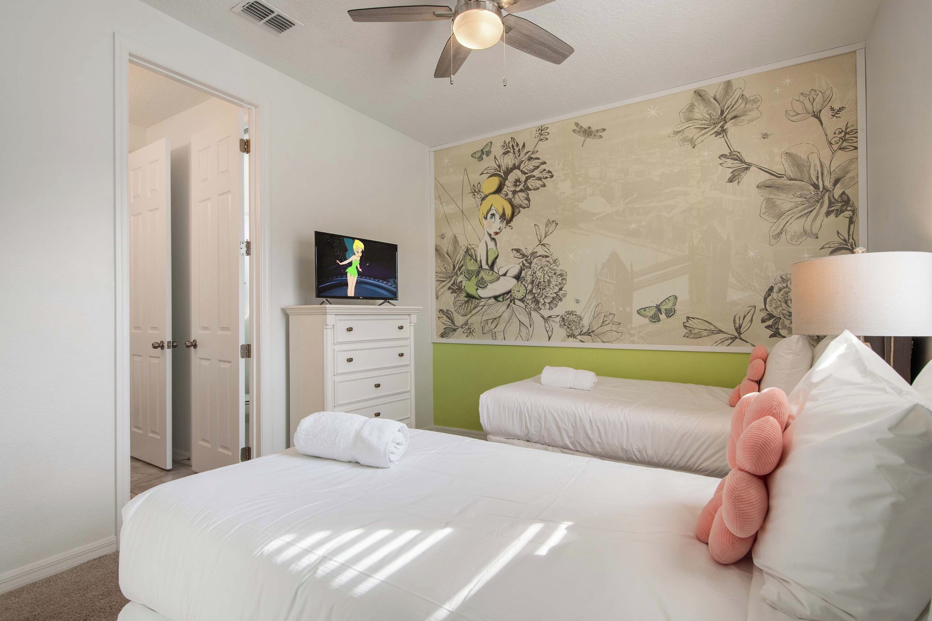 A hotel room with a bed, a television, a dresser, and a floral wallpaper.