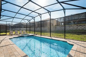 A swimming pool with a glass enclosure, surrounded by brick flooring and a grassy area. - Huge 9br/solara Resort/themed Rooms/games/disney! (Kissimmee)