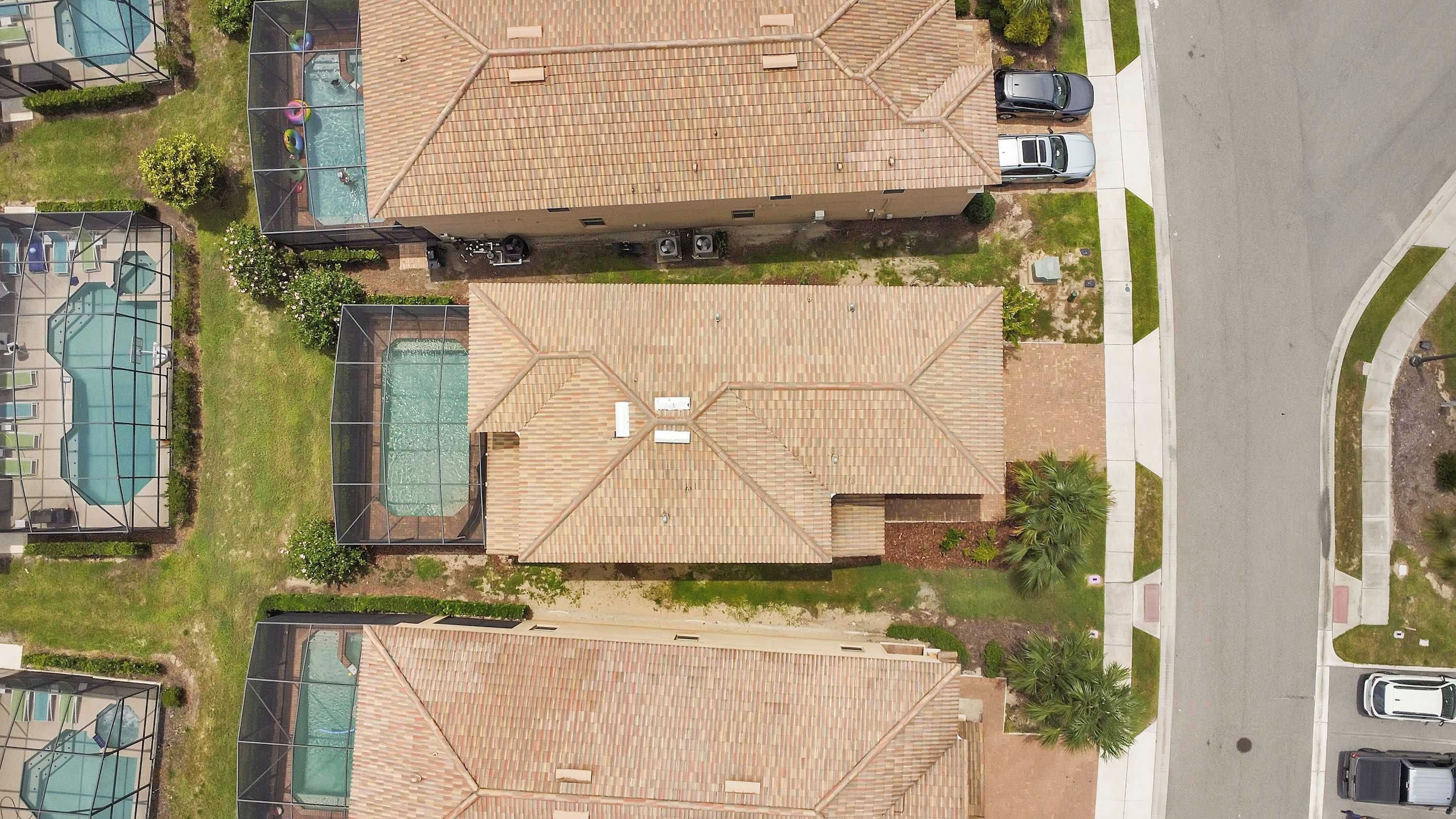 A residential area with multiple houses, each featuring a tiled roof and a swimming pool.