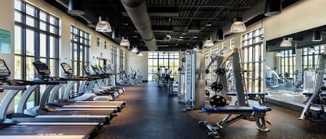 Une salle de sport équipée de tapis de course, d’appareils de musculation et de poids libres.
