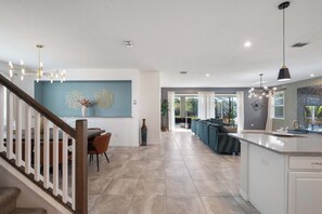 A spacious living area with a kitchen island, a dining area, and a staircase. - 11br Familyhome/games @ Solara + Resort Access! (Kissimmee)