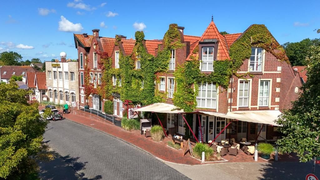 A row of traditional brick buildings with red-tiled roofs, some with ivy, and a street with a cobblestone road.