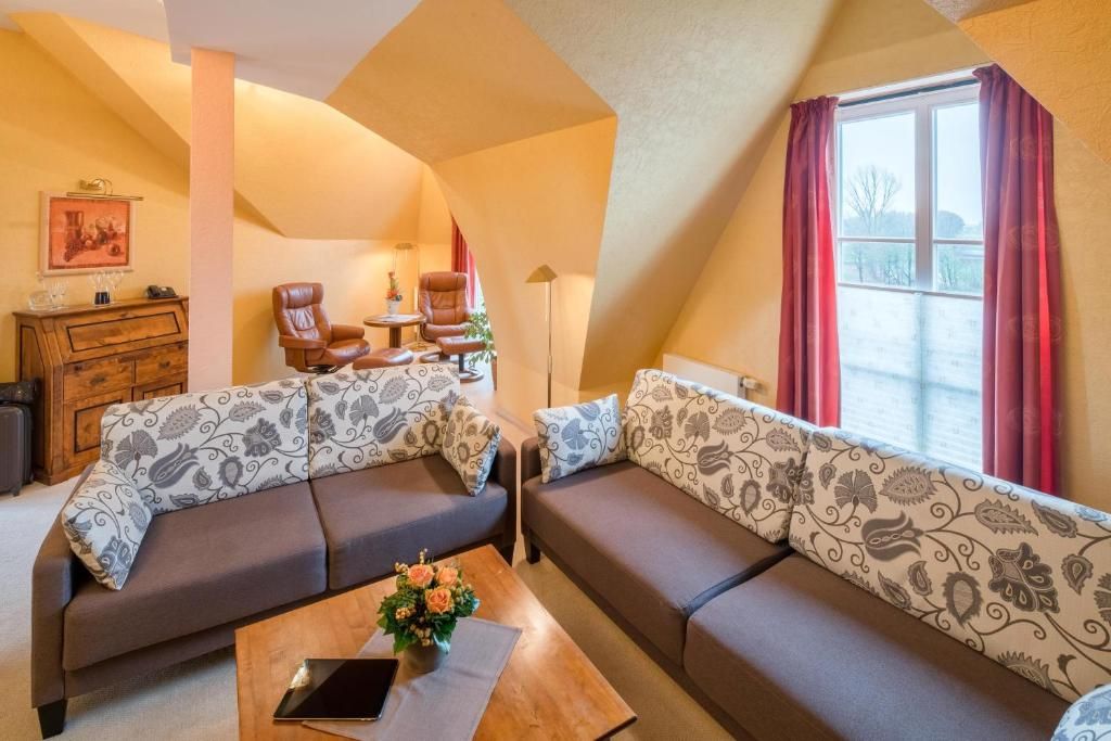 A cozy living room with two sofas, a coffee table, and a window with curtains.