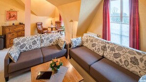 A cozy living room with two sofas, a coffee table, and a window with curtains. - Ringhotel Altes Zollhaus (Wangerland)