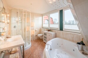 Un baño moderno con ducha de vidrio, bañera independiente y tocador con espejo.