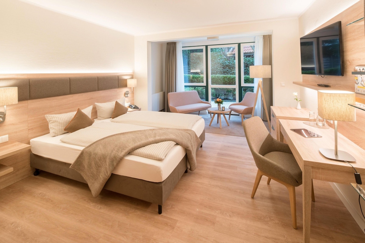 Habitación de hotel con una cama grande, un escritorio, una silla y un televisor.