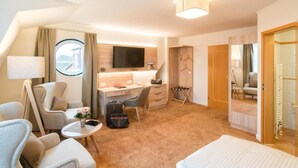 A hotel room with a bed, a desk, a chair, a TV, and a view of the outdoors. - Ringhotel Altes Zollhaus (Wangerland)