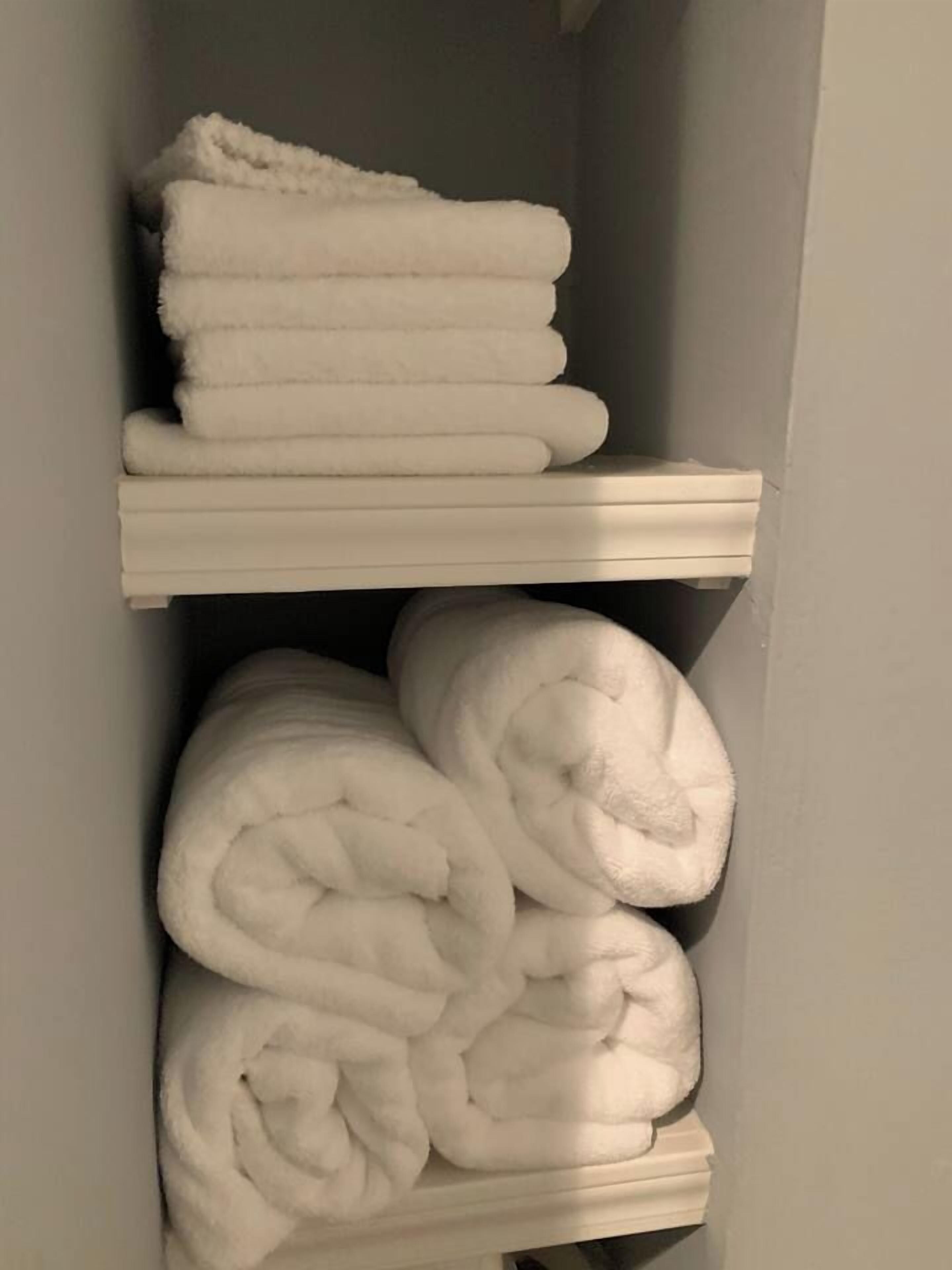 Un espace de rangement doté d’étagères où sont rangées, bien pliées, des serviettes blanches.