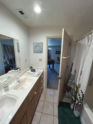 Un baño con lavamanos doble, un espejo y cortina de ducha.