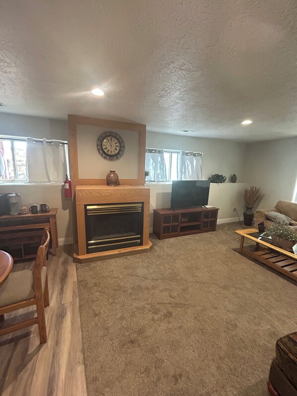 Una sala de estar con chimenea, televisor, mesa de comedor con sillas y sofá.