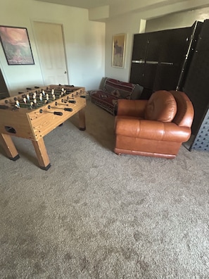 A room with a foosball table, a leather armchair, and a sofa with a patterned throw rug. - Relaxing 2 bdrm retreat near Zion with beautiful views sleeps eight, 2000 sq ft. (Hurricane)