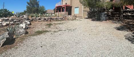 A residential property with a gravel driveway, a two-story house with a balcony, and surrounding landscaping.