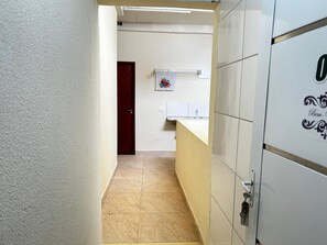 Ein schmaler Flur mit einer Tür am Ende, einem Handtuchhalter mit einem Handtuch und einem Waschtisch.