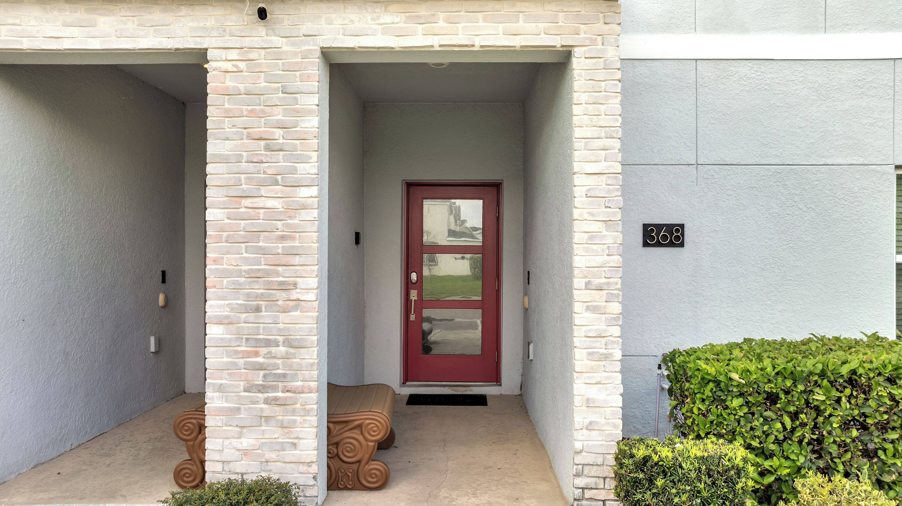 A building entrance with a red door, a mailbox, and a number plate.