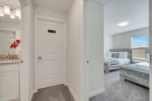 A hotel room with a private door, a bathroom with a vanity and mirror, and a bed with a view of the outdoors. - Dream Home With Pool Near Disney (Kissimmee)