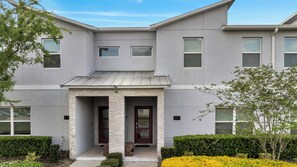 A modern two-story building with a stone entrance, numbered 378, and a well-maintained front yard with yellow flowers. - Dream Home With Pool Near Disney (Kissimmee)