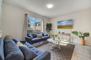 A living room with a sofa, a coffee table, and a painting on the wall. - Dream Home With Pool Near Disney (Kissimmee)