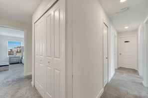 A hallway with white doors, a closet, and a view of a balcony. - Dream Home With Pool Near Disney (Kissimmee)