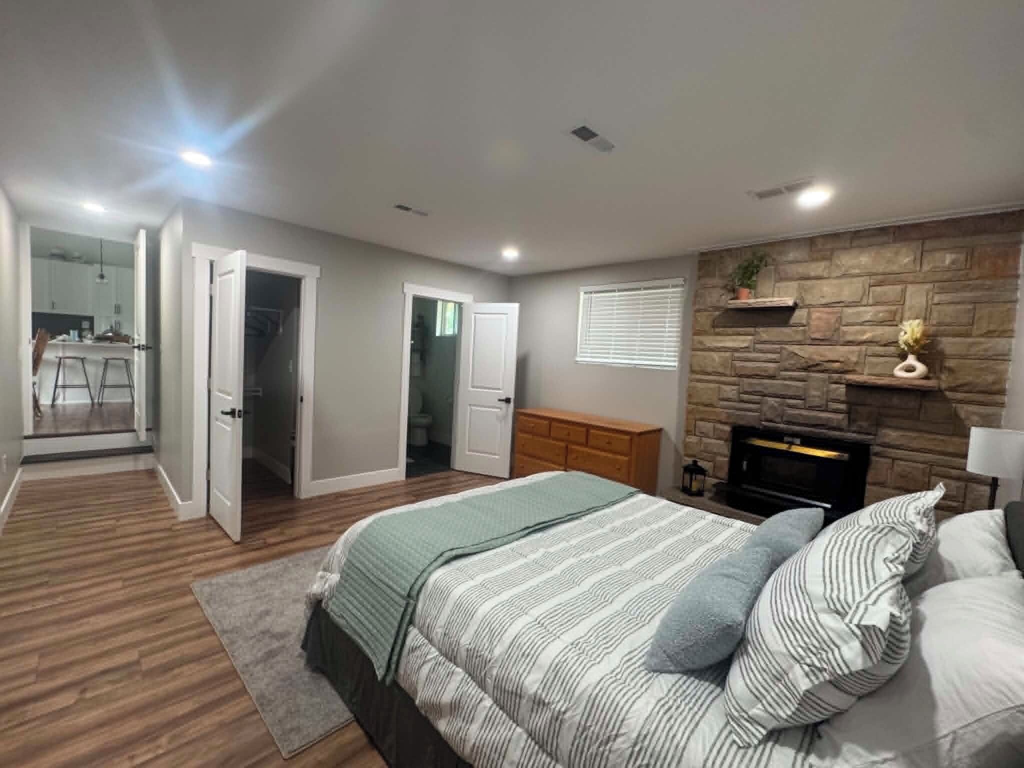 Un dormitorio con cama, chimenea y pared de piedra.
