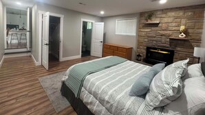 Un dormitorio con cama, chimenea y pared de piedra.
