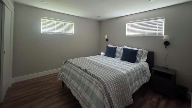 A bedroom with a bed, two bedside lamps, and two windows with blinds. - Welcome to Rosehill (Dayton)