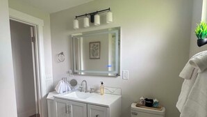 Un baño moderno con tocador blanco, inodoro y zona de ducha.