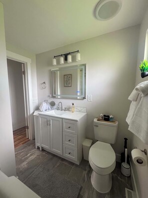 Un baño moderno con tocador blanco, inodoro y zona de ducha.