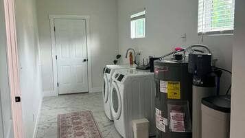 Un cuarto de lavandería con lavadora, secadora y calentador de agua.