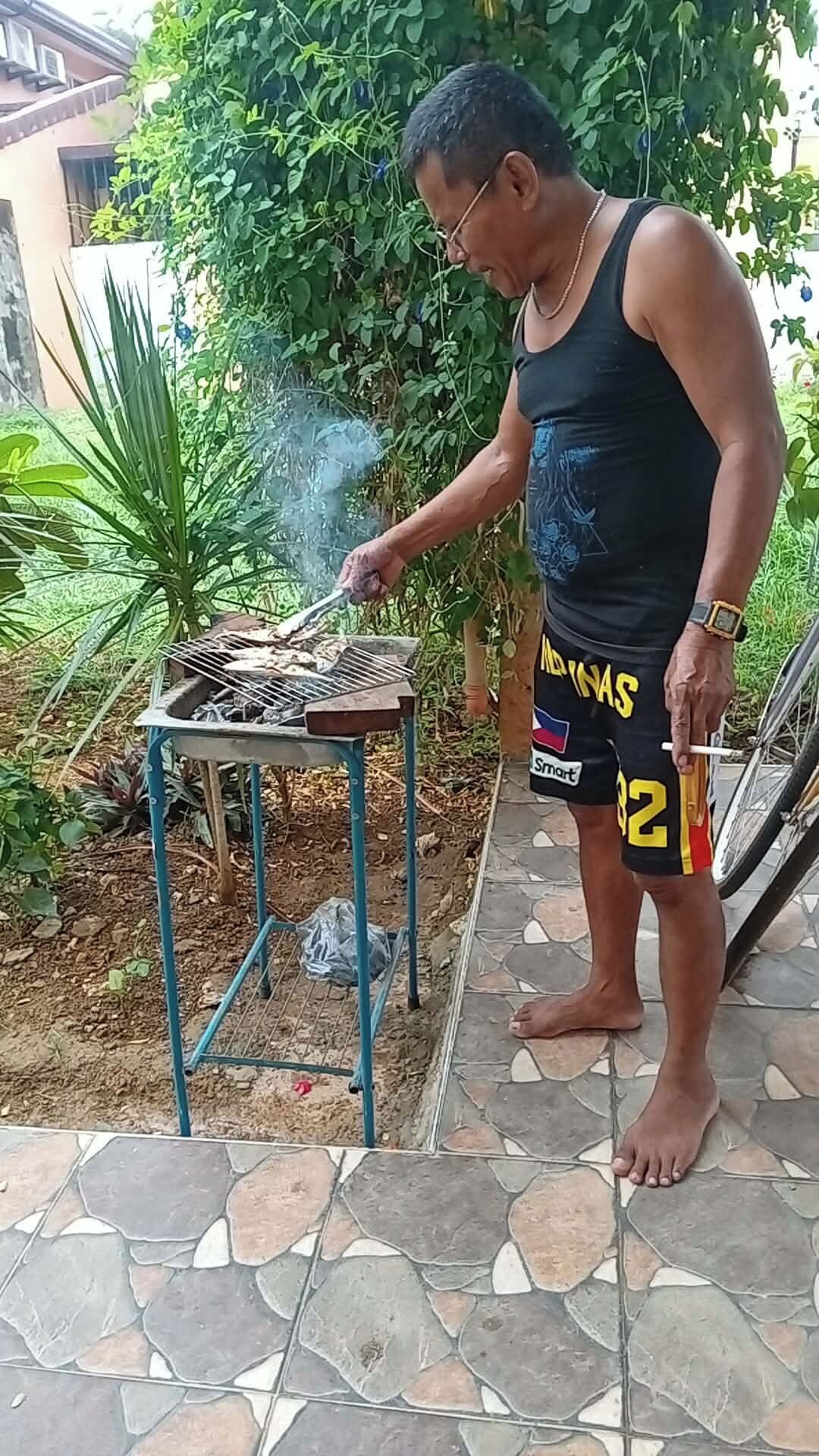 Jemand grillt draußen, mit einem Metalltisch und einem Fahrrad in der Nähe.