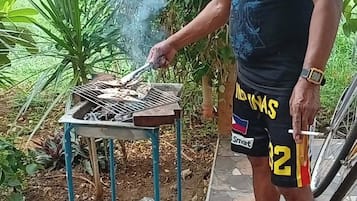 Jemand grillt draußen, mit einem Metalltisch und einem Fahrrad in der Nähe.