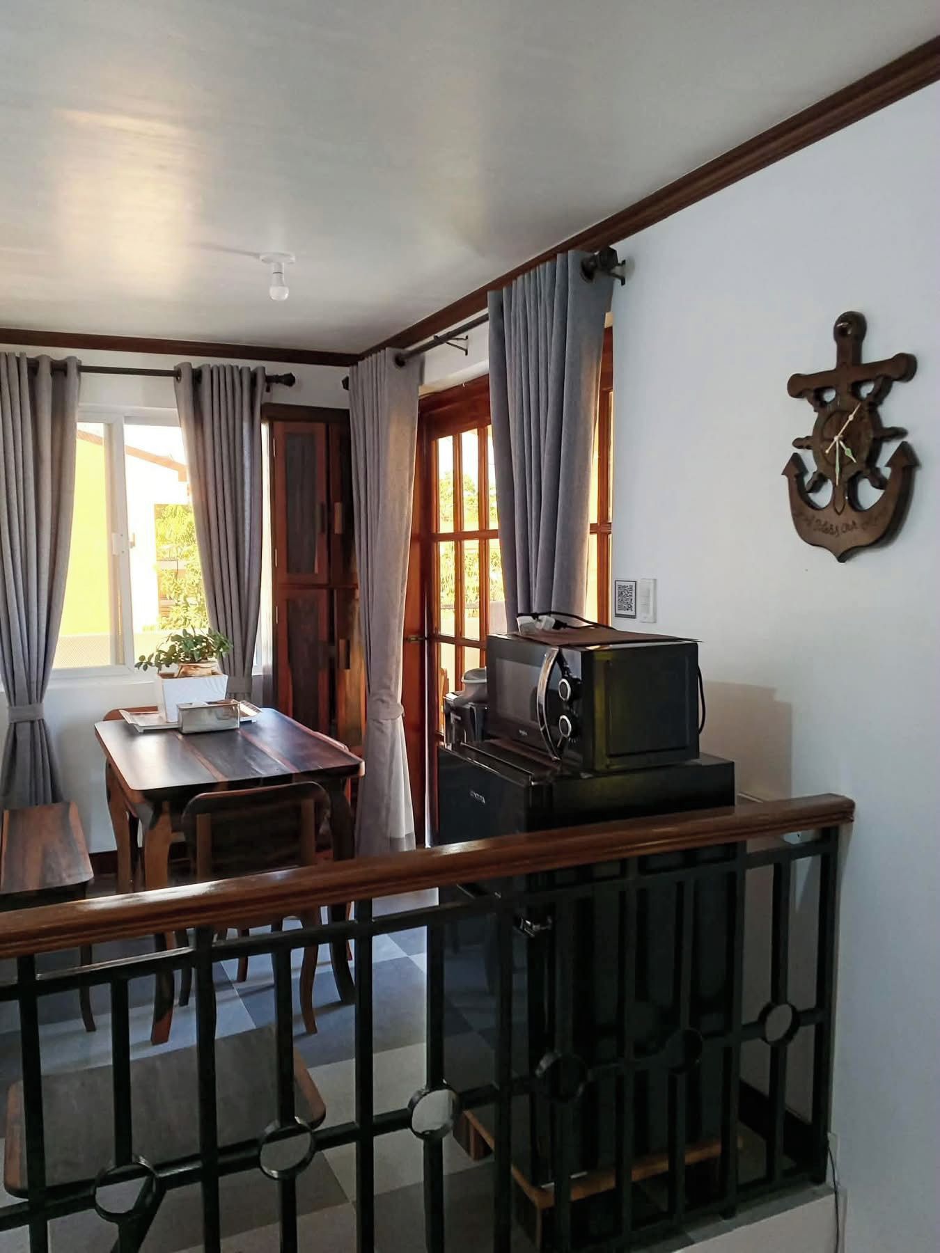 A room with a dining table, chairs, a television, and a decorative anchor on the wall.