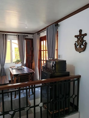 Une pièce comprenant une table à manger, des chaises, un téléviseur et une ancre décorative accrochée au mur.