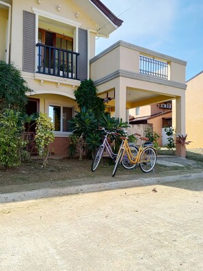 Edificio residencial de dos plantas con un balcón y una bicicleta estacionada en la parte delantera.