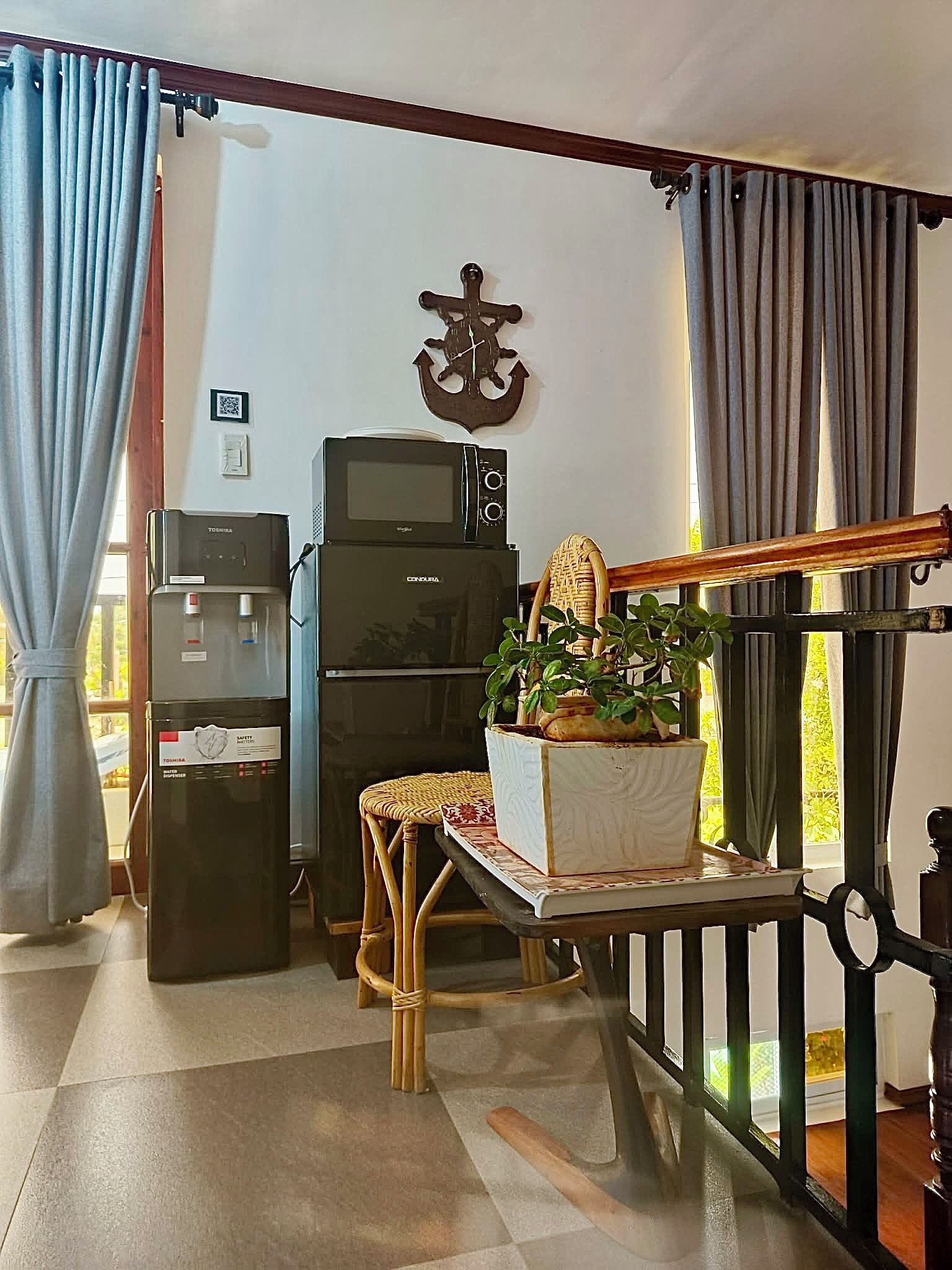Un espacio habitable compacto con kitchenette, una zona de comedor con una silla de mimbre y una pequeña mesa.