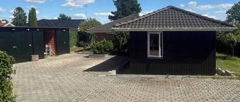 A residential property with a paved driveway, a small shed, and a brick house.