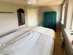 Ett sovrum med en säng, en garderob, en spegel och en hängande lampa.