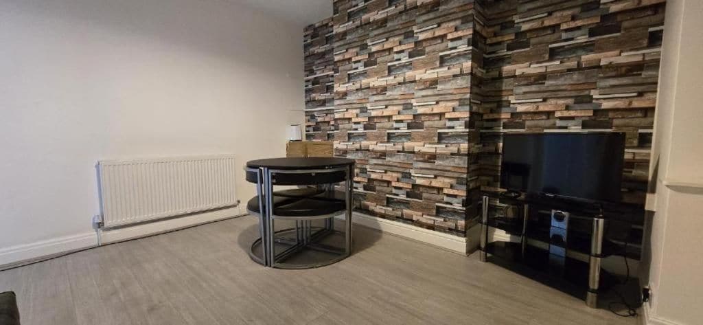 A room with a modern fireplace, a television, and a small round table.