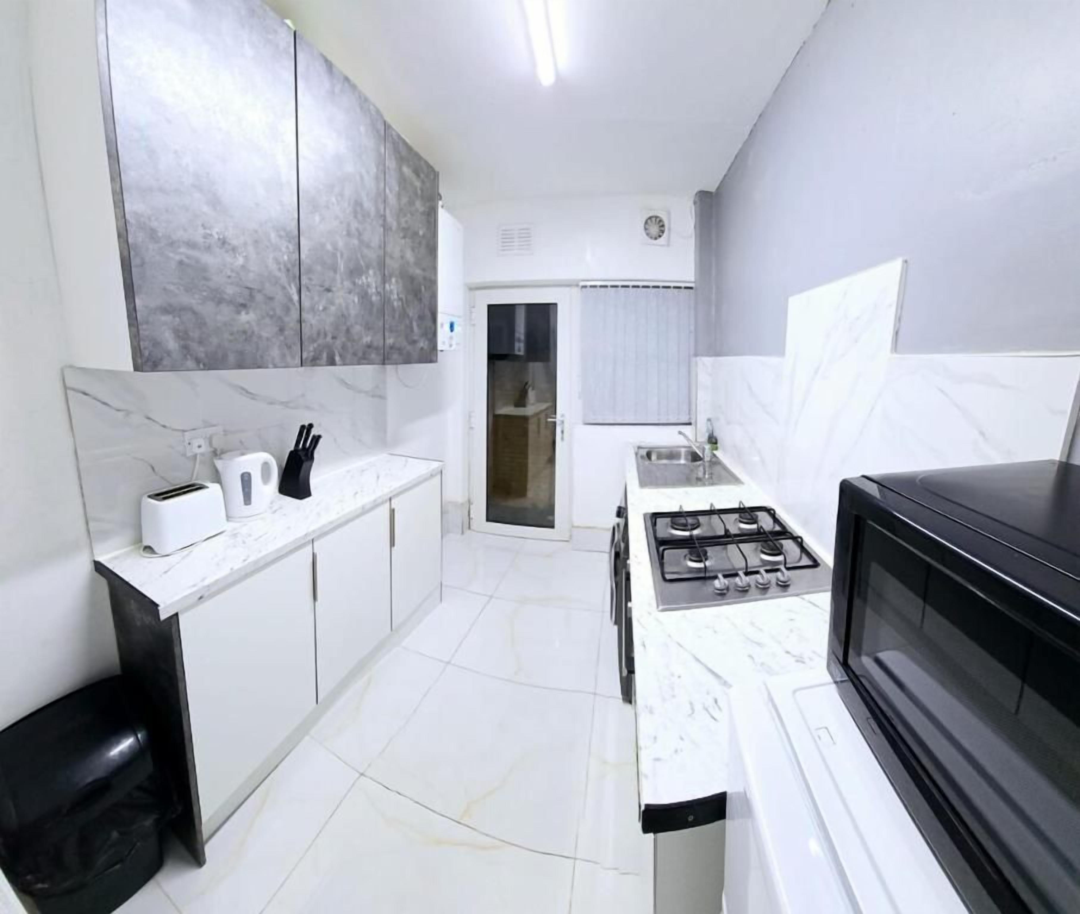 A compact kitchen with white cabinetry, a gas stove, a microwave, and a black countertop.
