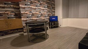Et værelse med moderne design, der har en stenvæg, et rundt bord med metalstel, en sort lædersofa og et fjernsyn, der viser Netflix-logoet.