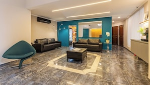 Una sala moderna con una pared de acento color turquesa, dos sofás de cuero, una mesa de centro y una silla turquesa original.