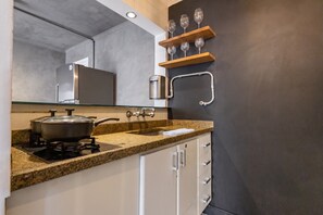 A modern kitchen with granite countertops, a gas stove, and a built-in oven. - Matiz Manhattan Hotel - Gym Pool & Sauna (São Paulo)