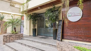 L’entrée d’un restaurant, avec une enseigne, des marches menant à la porte et des plantes en pot.