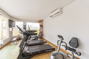 Un gimnasio con cintas de correr, una elíptica y una bicicleta estática.