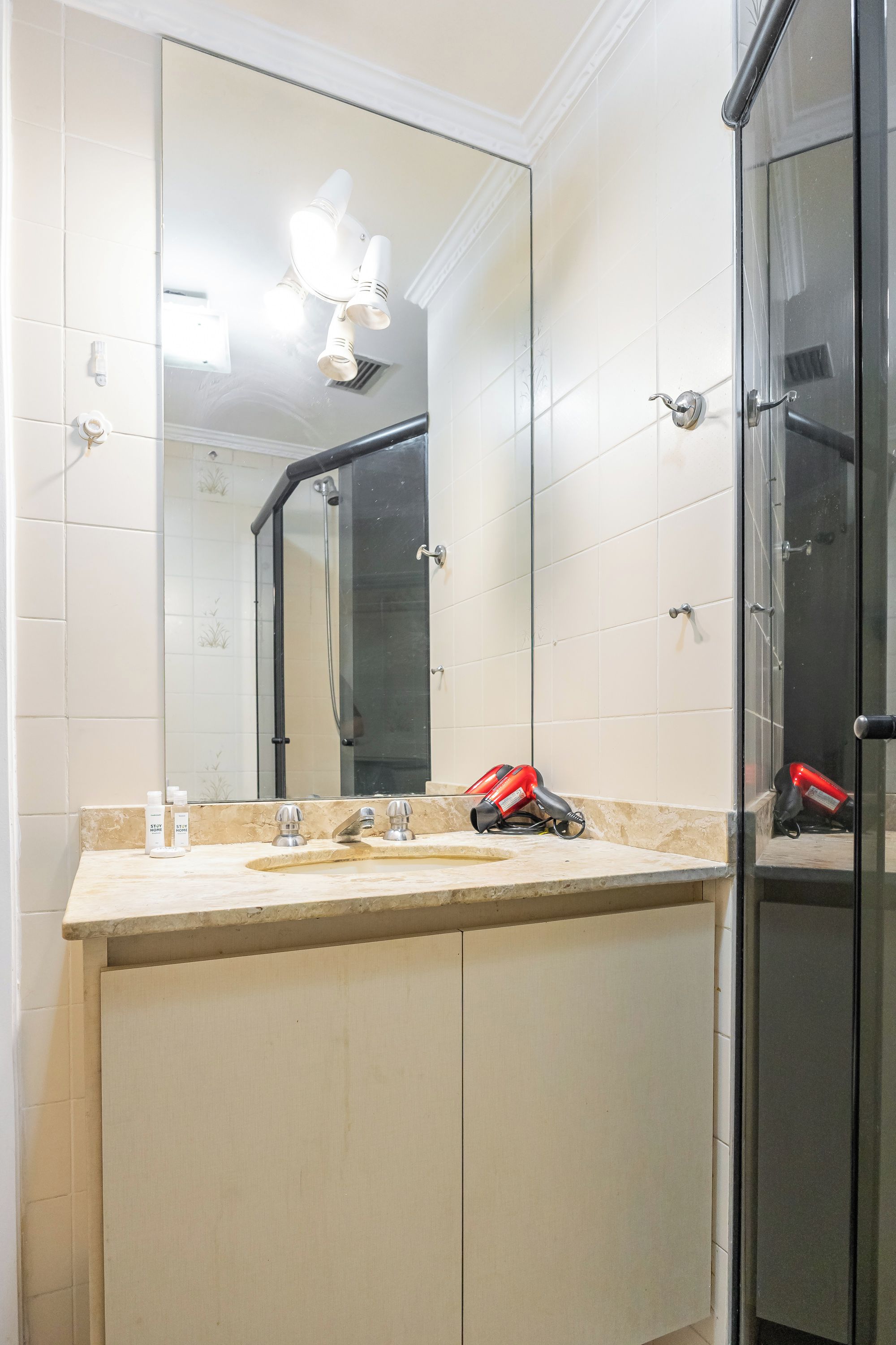 A bathroom with a large mirror, a sink with a vanity, and a shower area.