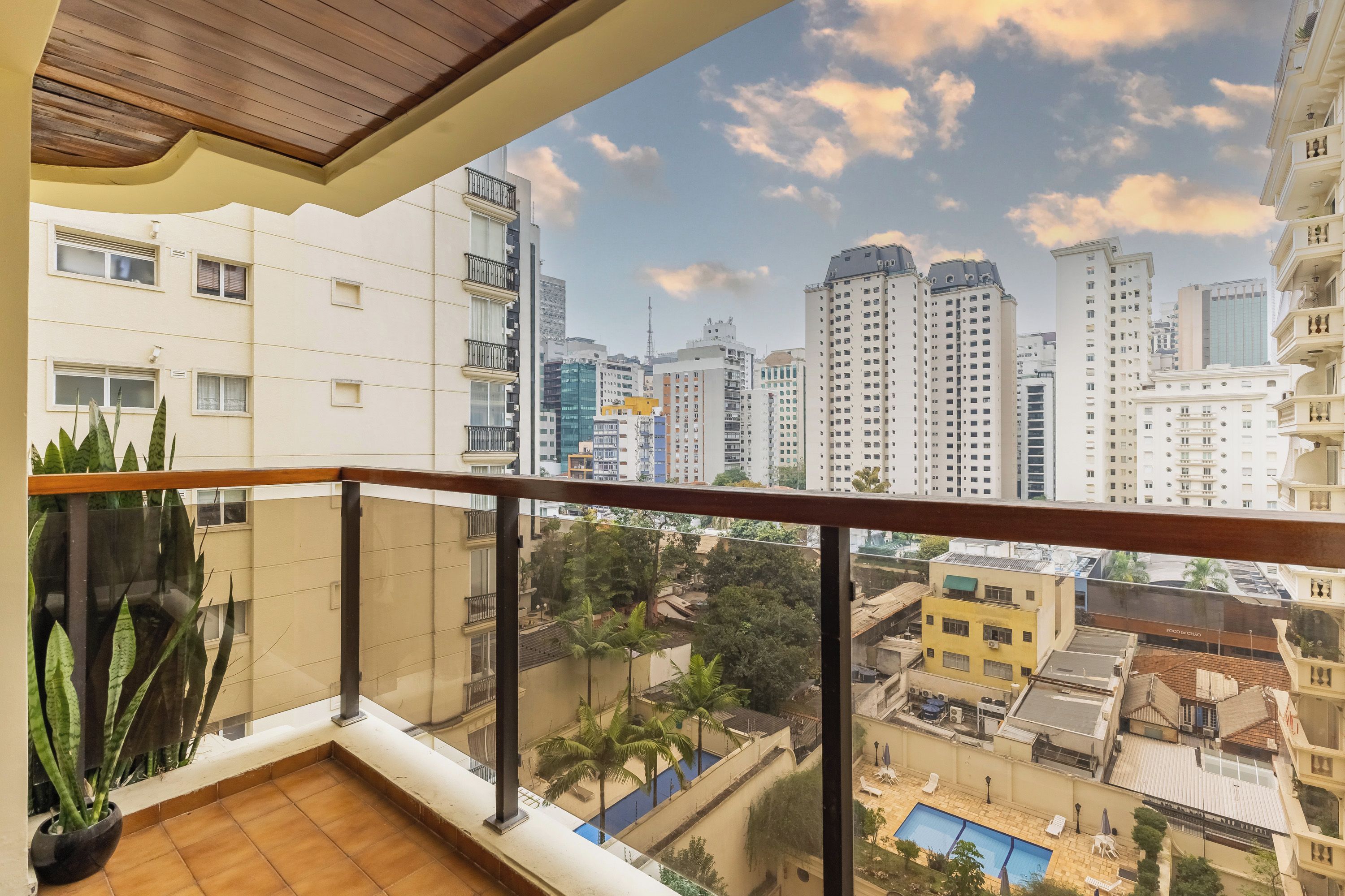 A balcony with a view of a cityscape, including high-rise buildings and a clear sky.