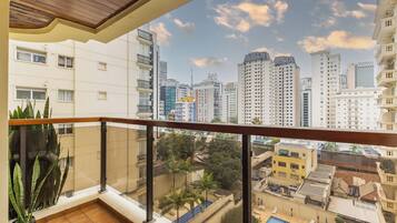 A balcony with a view of a cityscape, including high-rise buildings and a clear sky.